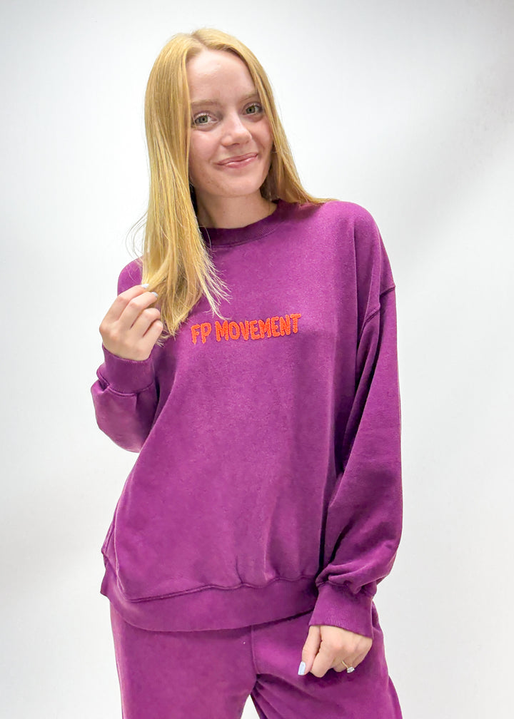 Women's purple crew neck sweatshirt with orange "FP Movement" embroidered chest graphic