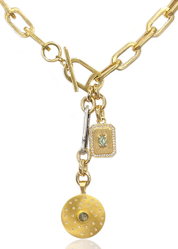 Brushed gold toggle necklace with a silver link and two gold CZ charms on a white background