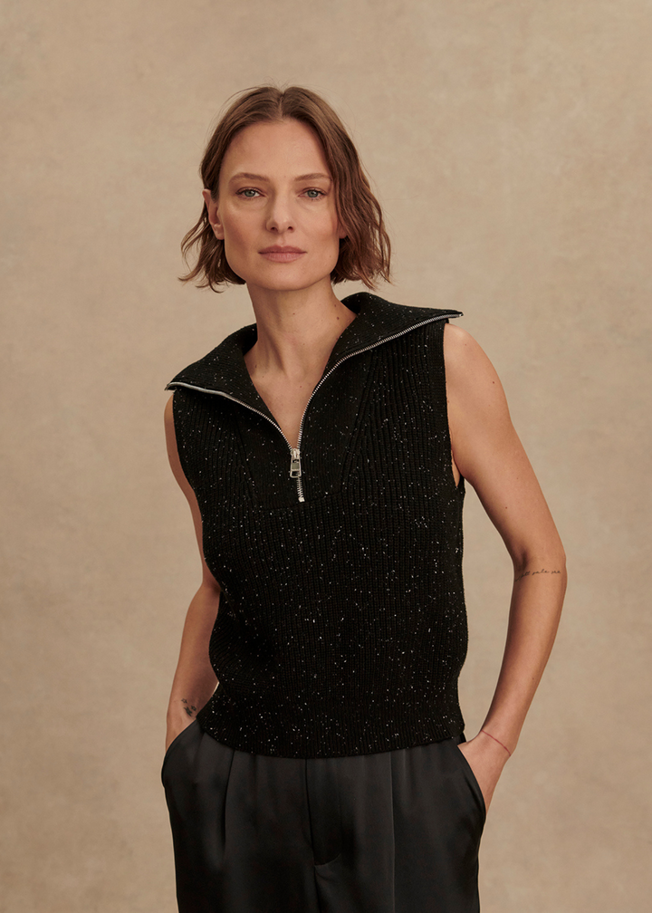 Woman wearing a black knitted vest with a quarter zip neckline