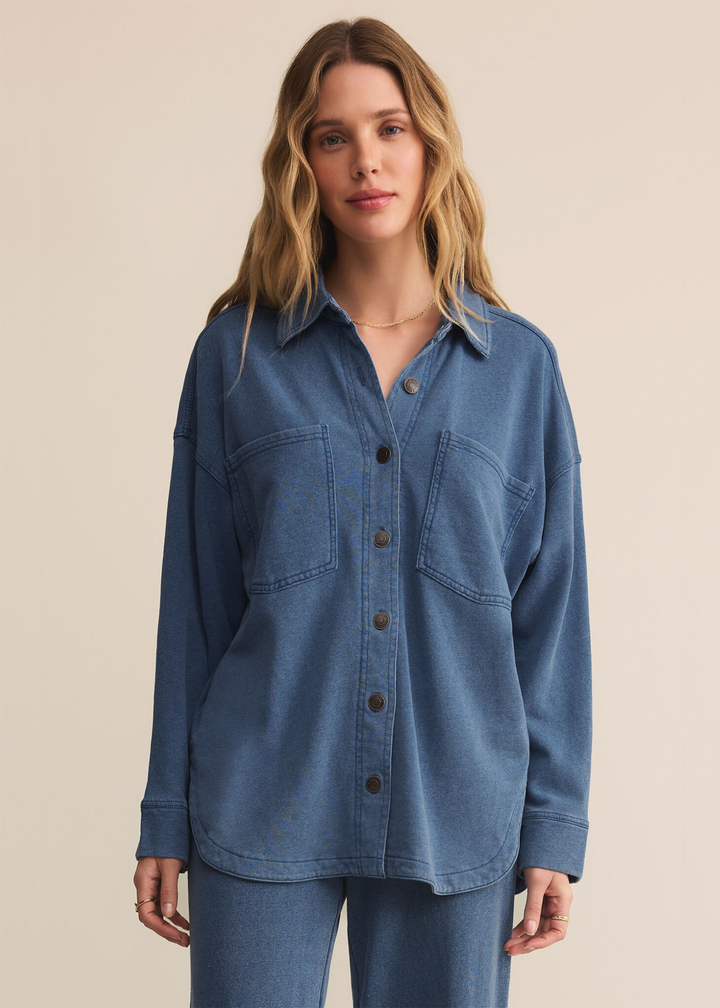 Woman wearing a blue knit denim shirt in front of a grey background