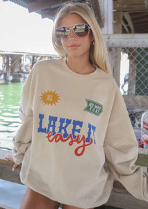 tan oversized crew neck sweatshirt with "lake it easy" graphic on front and cute graphic details throughout chest, sleeves, and back