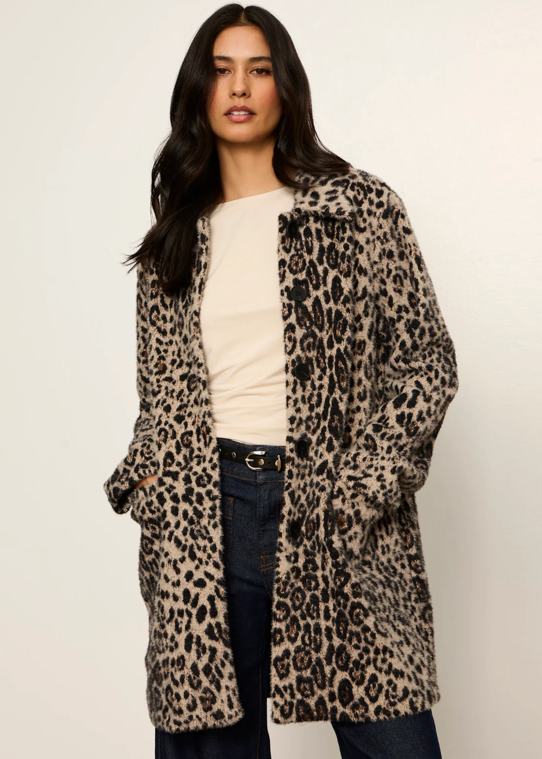 Woman wearing a leopard print coat with hands in her pockets.