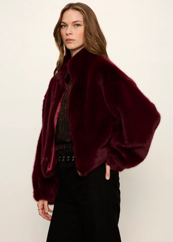 A woman wearing a maroon fur jacket.
