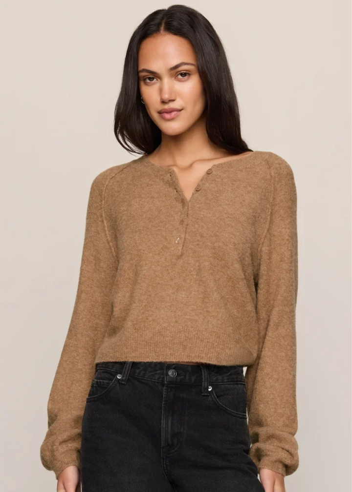 Woman wearing a brown sweater and black jeans.