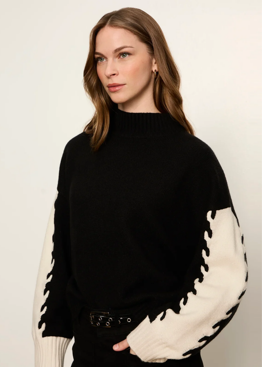 Woman wearing black and bone color block sweater.