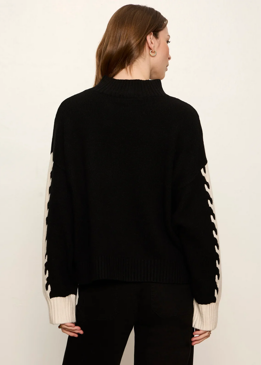 Woman wearing black and bone color block sweater.