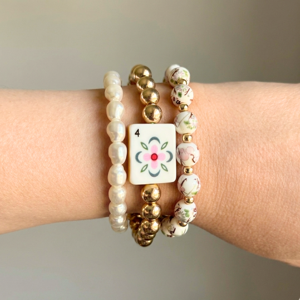 Stack of beaded bracelets on a wrist with a neutral background