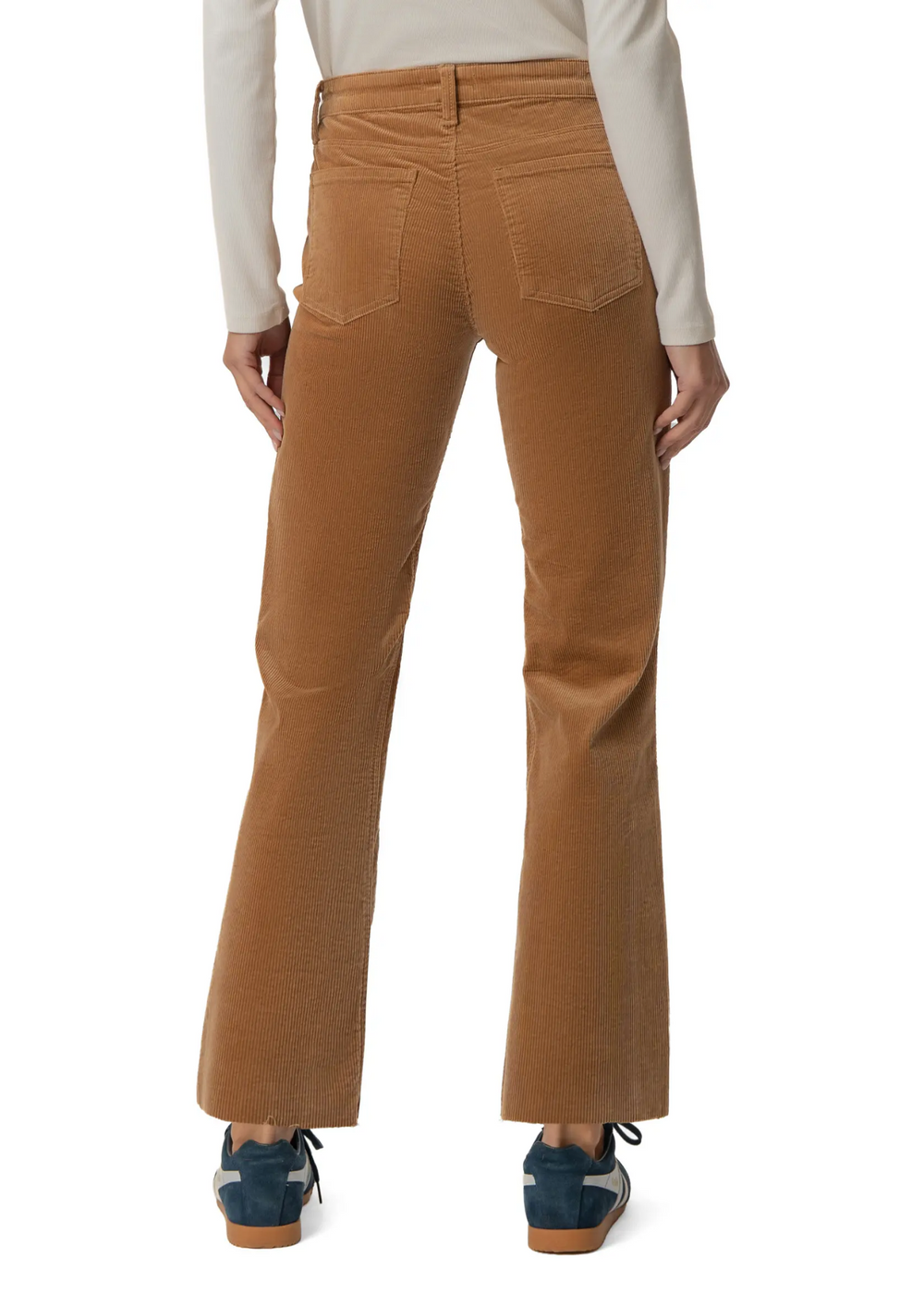 A person shown from the back wearing tan corduroy flare pants, a cream long-sleeve top, and blue sneakers against a plain white studio background.