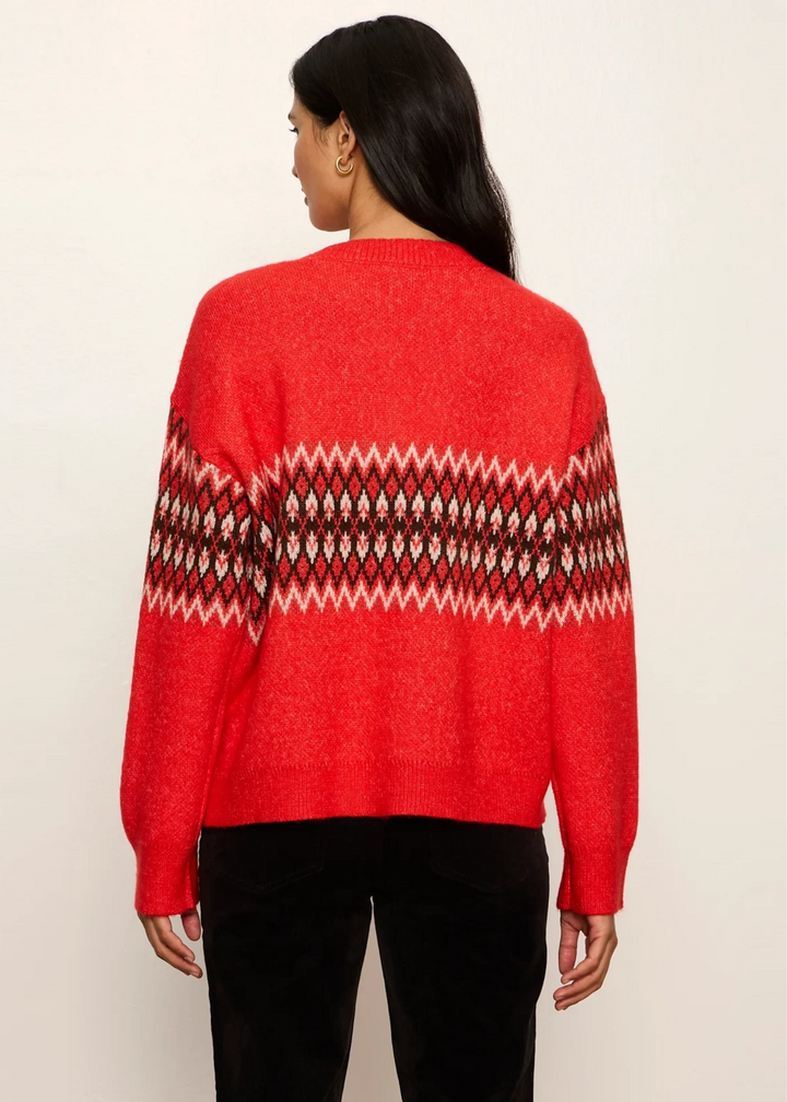 Woman wearing a red-hot argyle sweater with black pants and facing backwards.