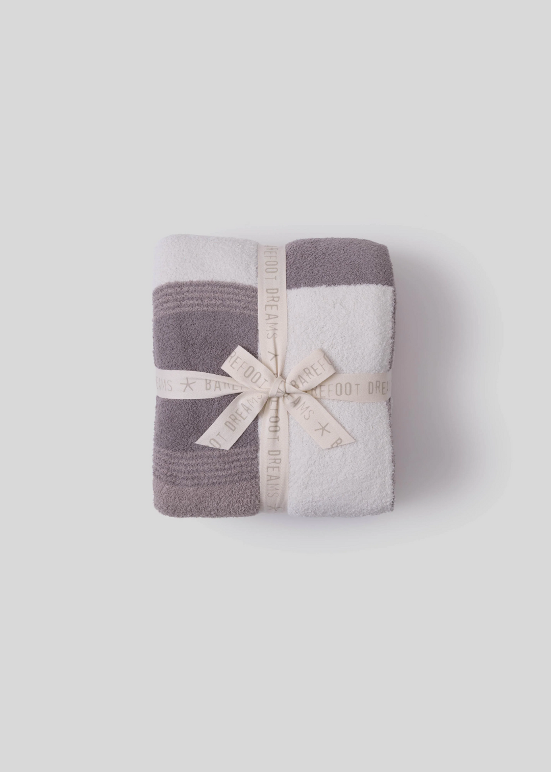 Brown and cream block patterned blanket folded with a bow on a grey background