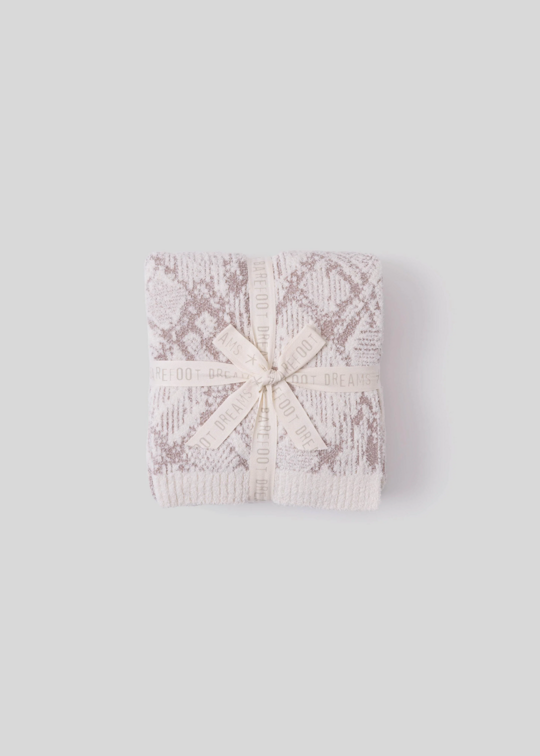Cream and taupe blanket folded with a bow on a grey background