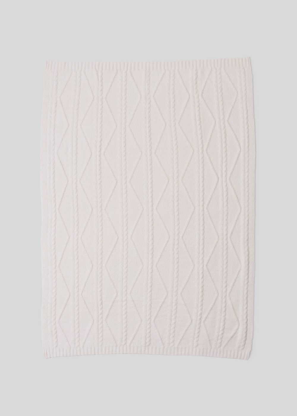 A cream blanket with a woven pattern laying on a white background