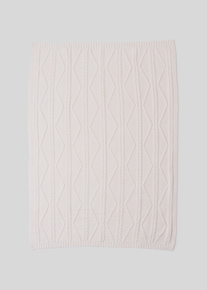 A cream blanket with a woven pattern laying on a white background