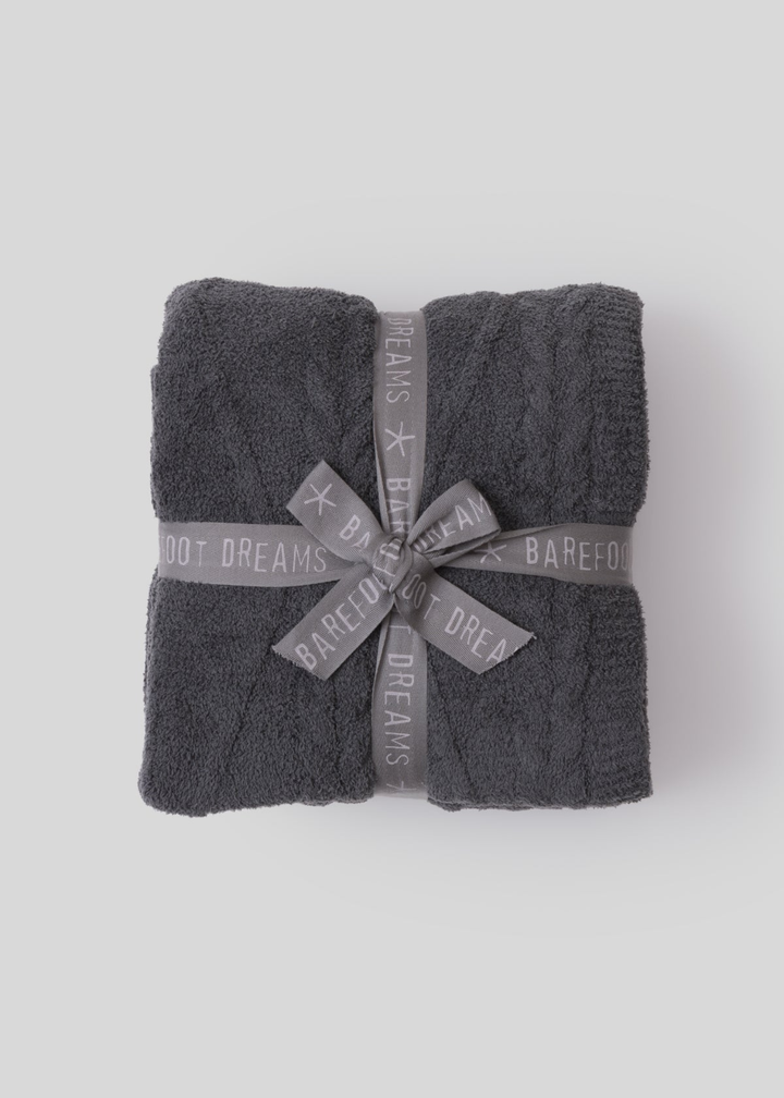 Grey folded blanket tied with a grey ribbon sitting on a white background