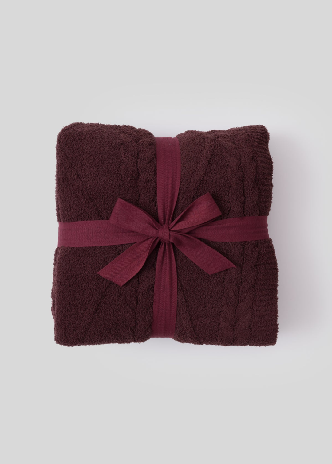 Maroon blanket tied with a maroon ribbon sitting on a white background