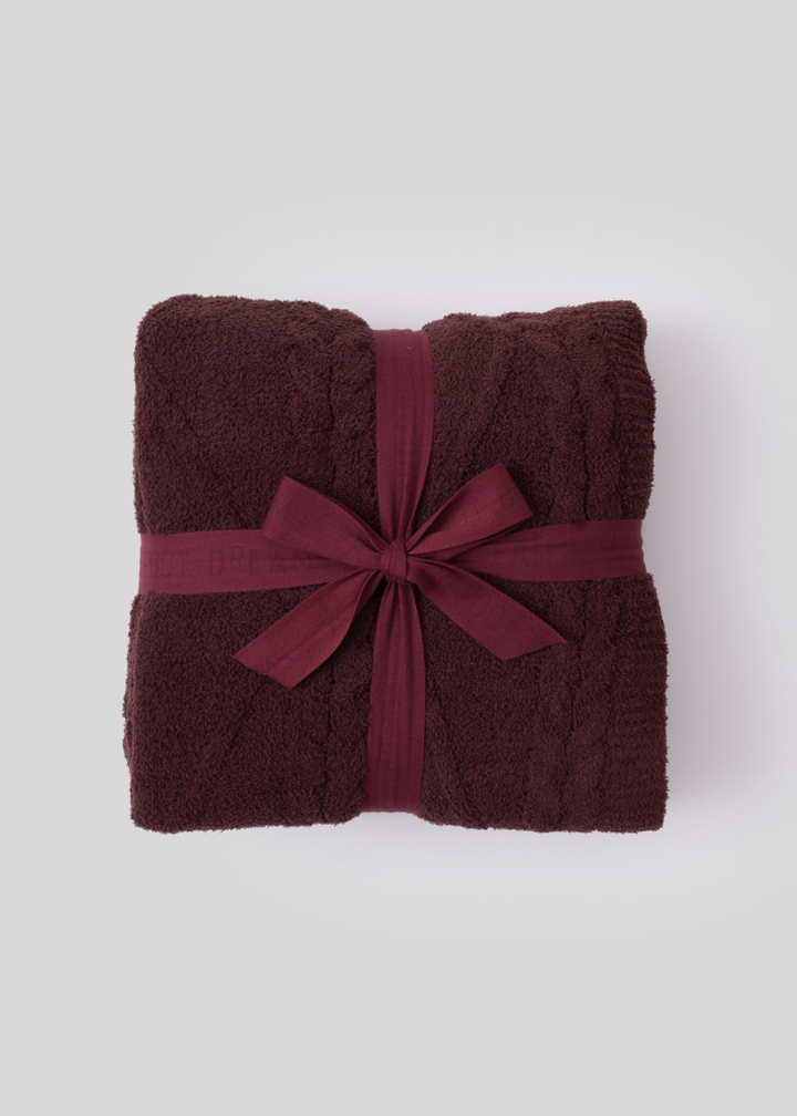 Maroon blanket tied with a maroon ribbon sitting on a white background