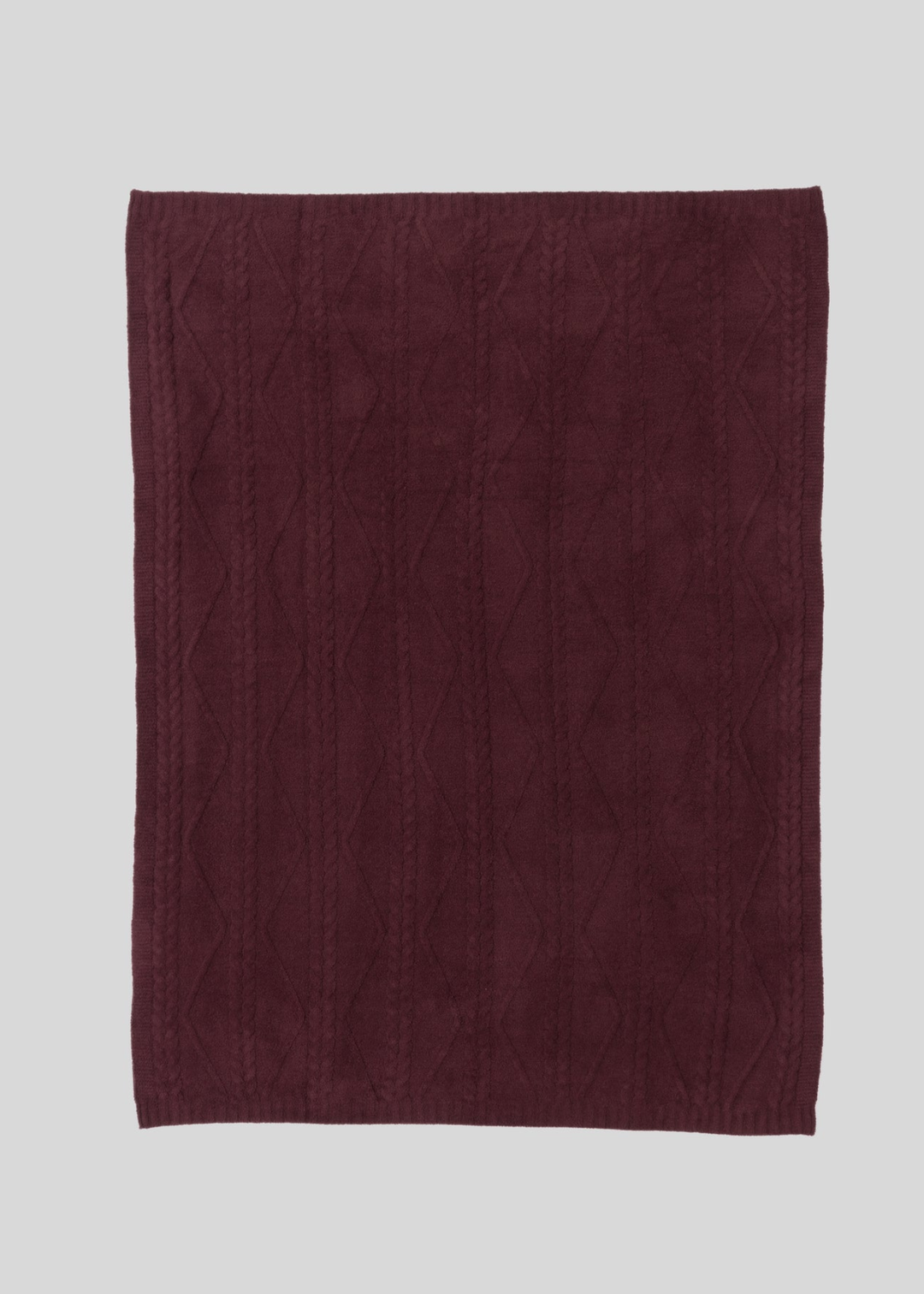 Maroon blanket with a woven pattern laying on a white background