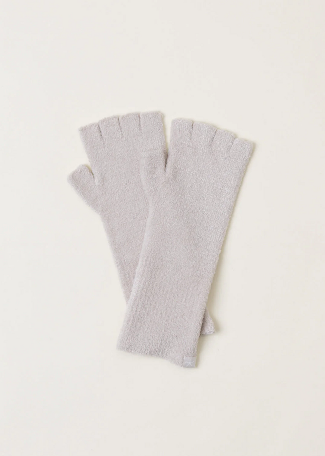 A pair of light grey fingerless gloves laying on a white background