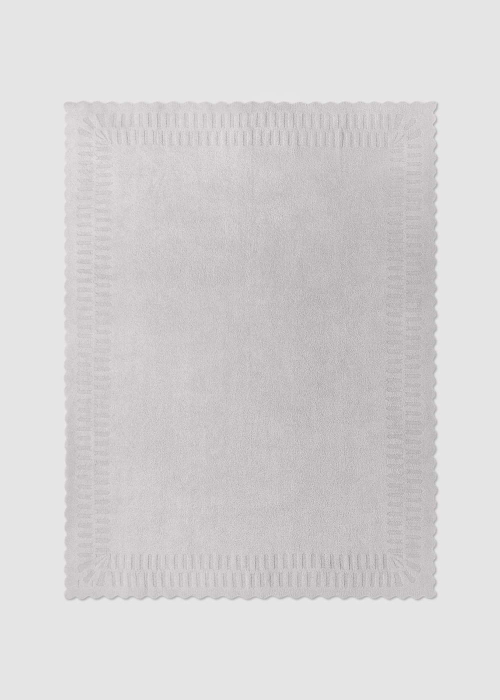 Grey blanket with scallop edges laying on a grey background