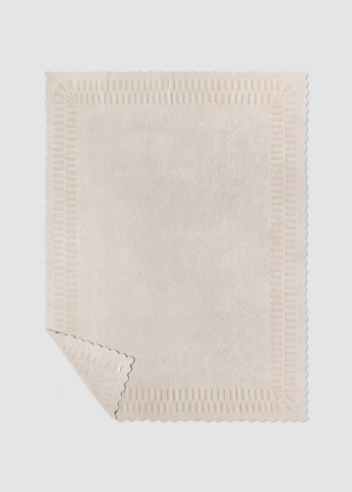Cream blanket laying on a grey background