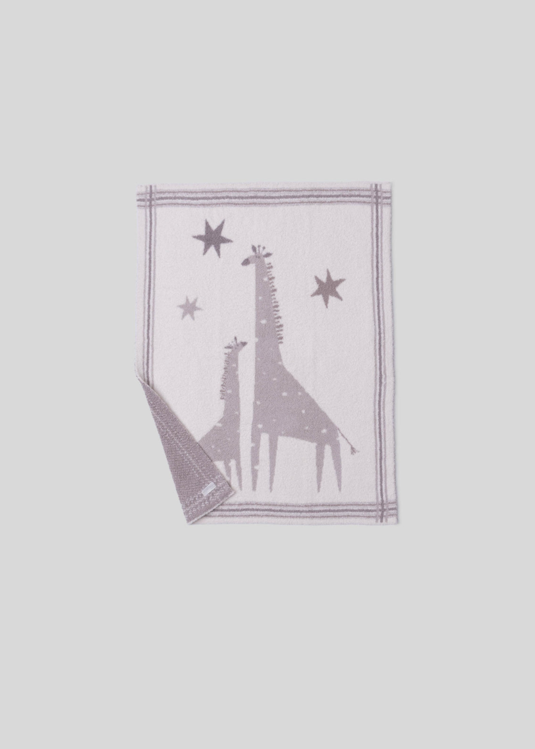 Pink and cream blanket with a giraffe graphic and a striped border with a corner folded on a white background