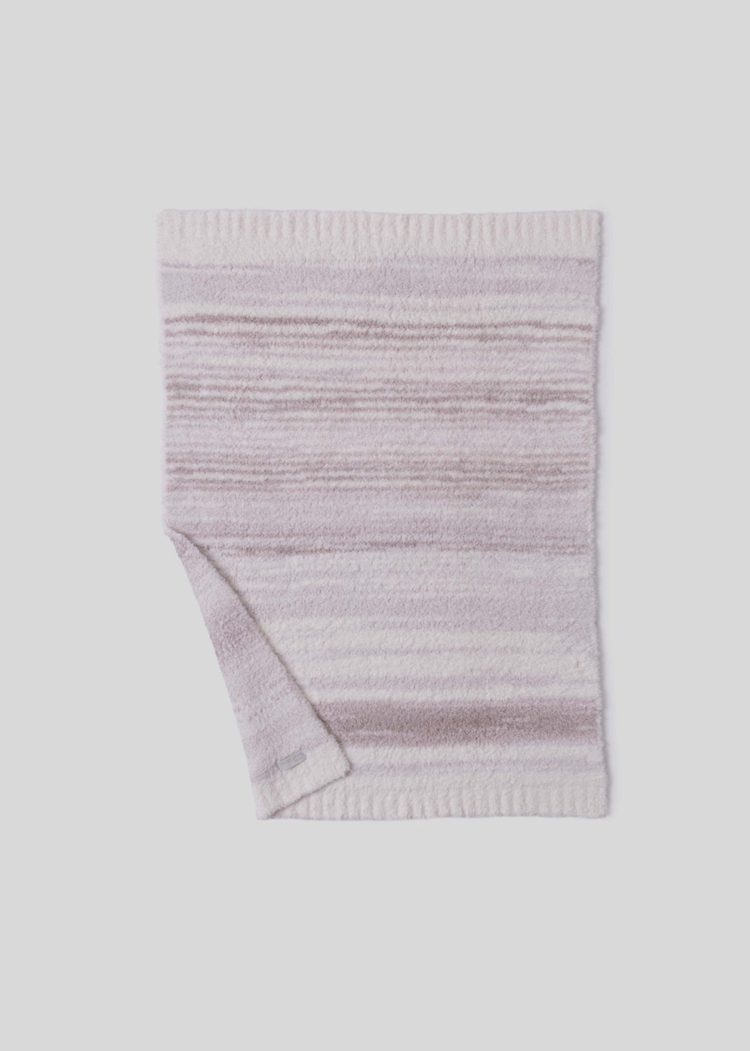 Pink and cream striped blanket with a corner folded laying on a white background 