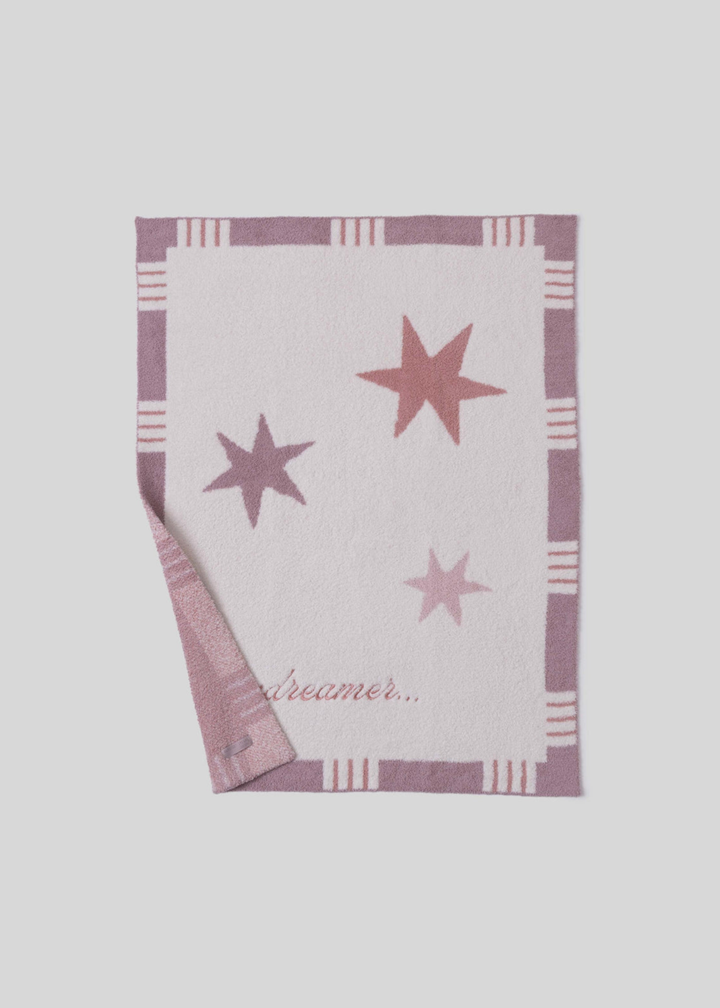 Pink blanket with stars and a striped border and "daydreamer..." pink embroidery with a corner folded