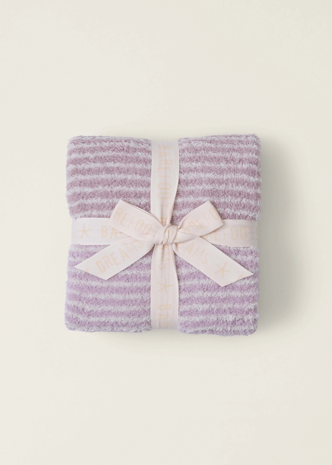 A pink striped blanket folded with a ribbon on a white background