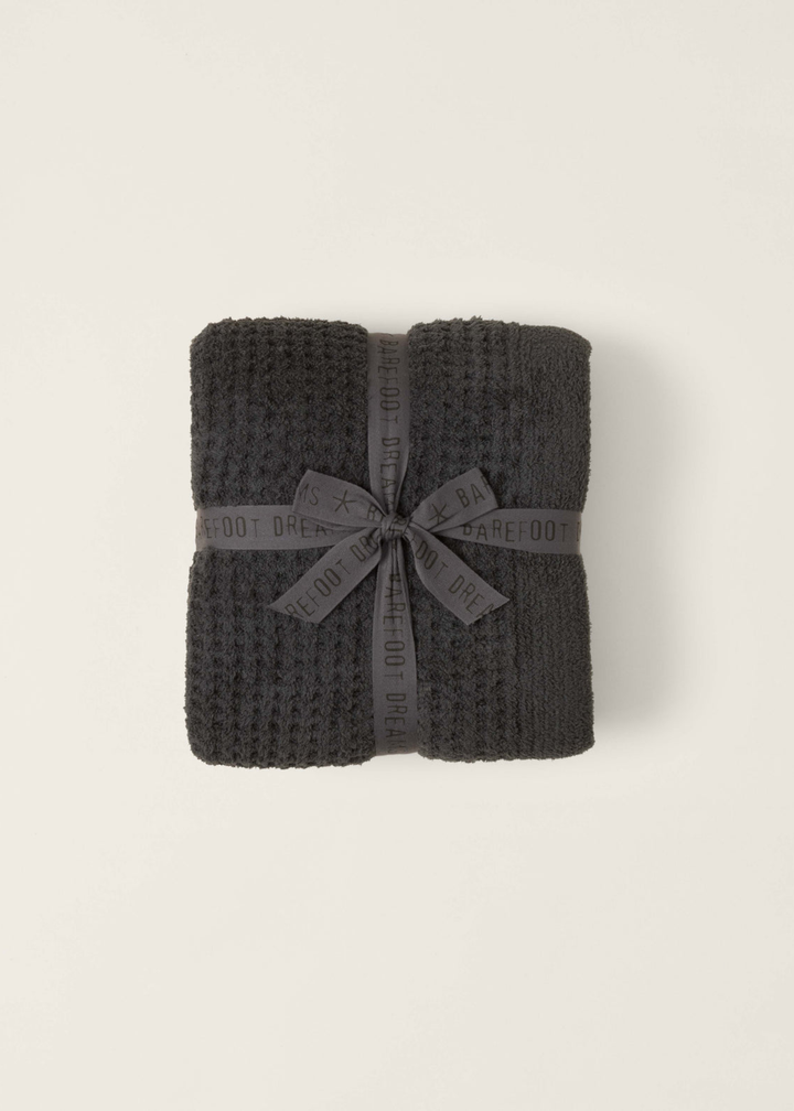 Dark grey waffle knit blanket folded with a grey bow on a white background