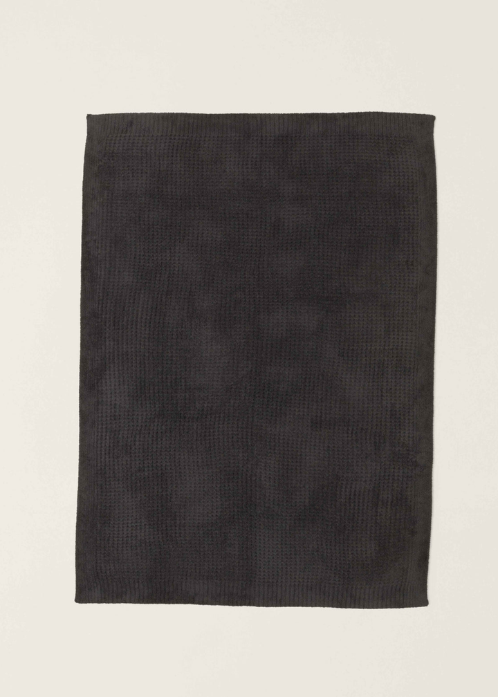 Dark grey waffle knit blanket laying on a white background