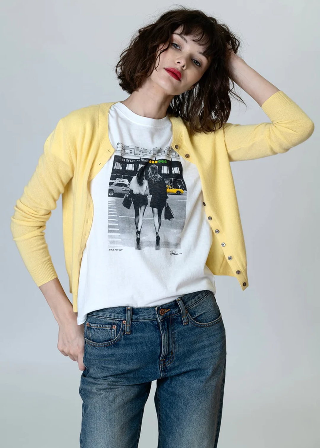 Woman wearing a graphic tee with jeans and a yellow cardigan