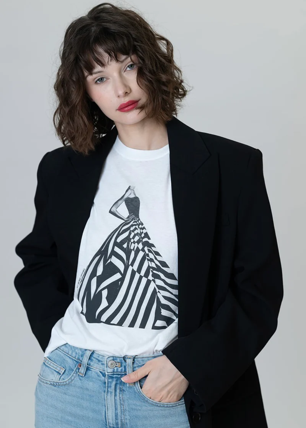 Woman wearing a white graphic tee with a black & white dress graphic with jeans and a black blazer