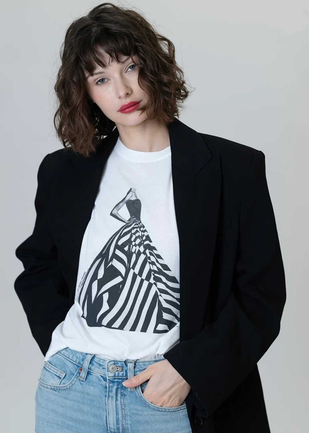 Woman wearing a white graphic tee with a black & white dress graphic with jeans and a black blazer