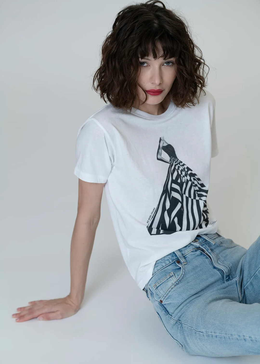 Woman wearing a white graphic tee with a black & white dress graphic with jeans