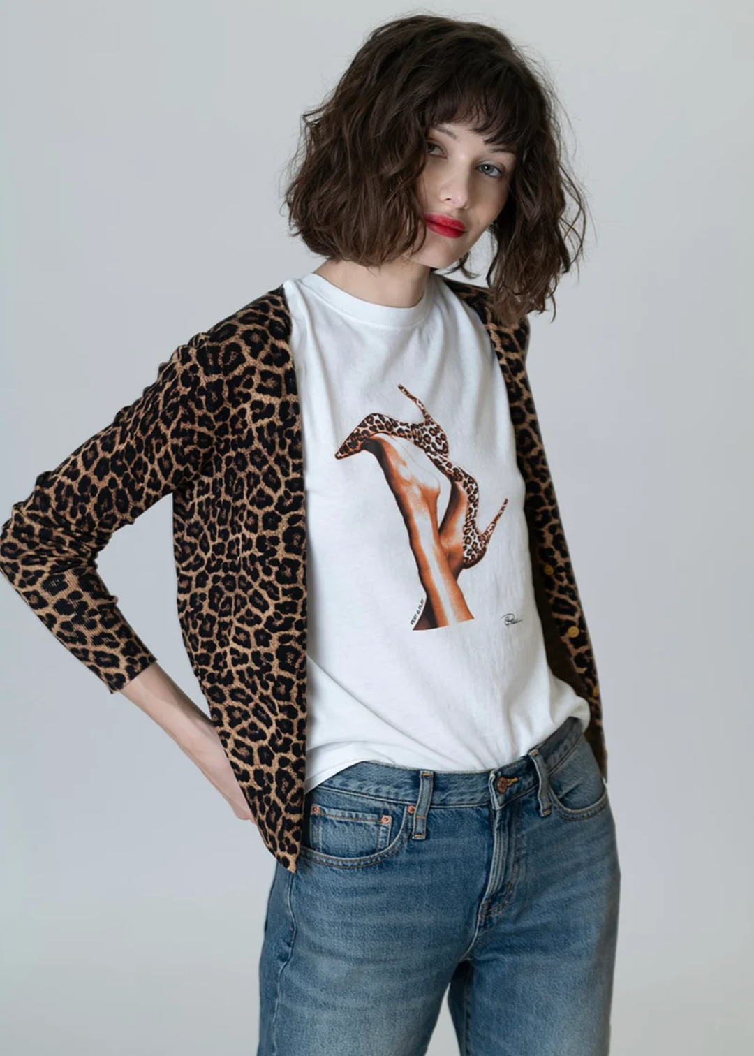 Woman wearing a white tee with a graphic of leopard print heels with jeans and a leopard print cardigan