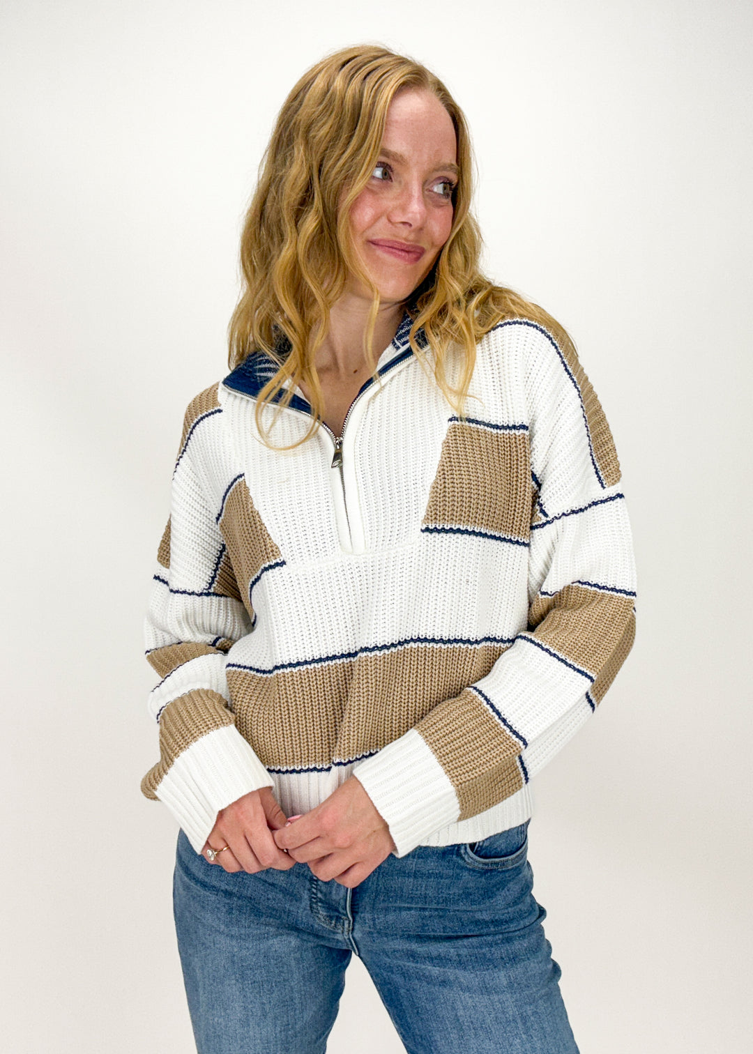 woman wearing white, tan, and blue stripe half zip sweater