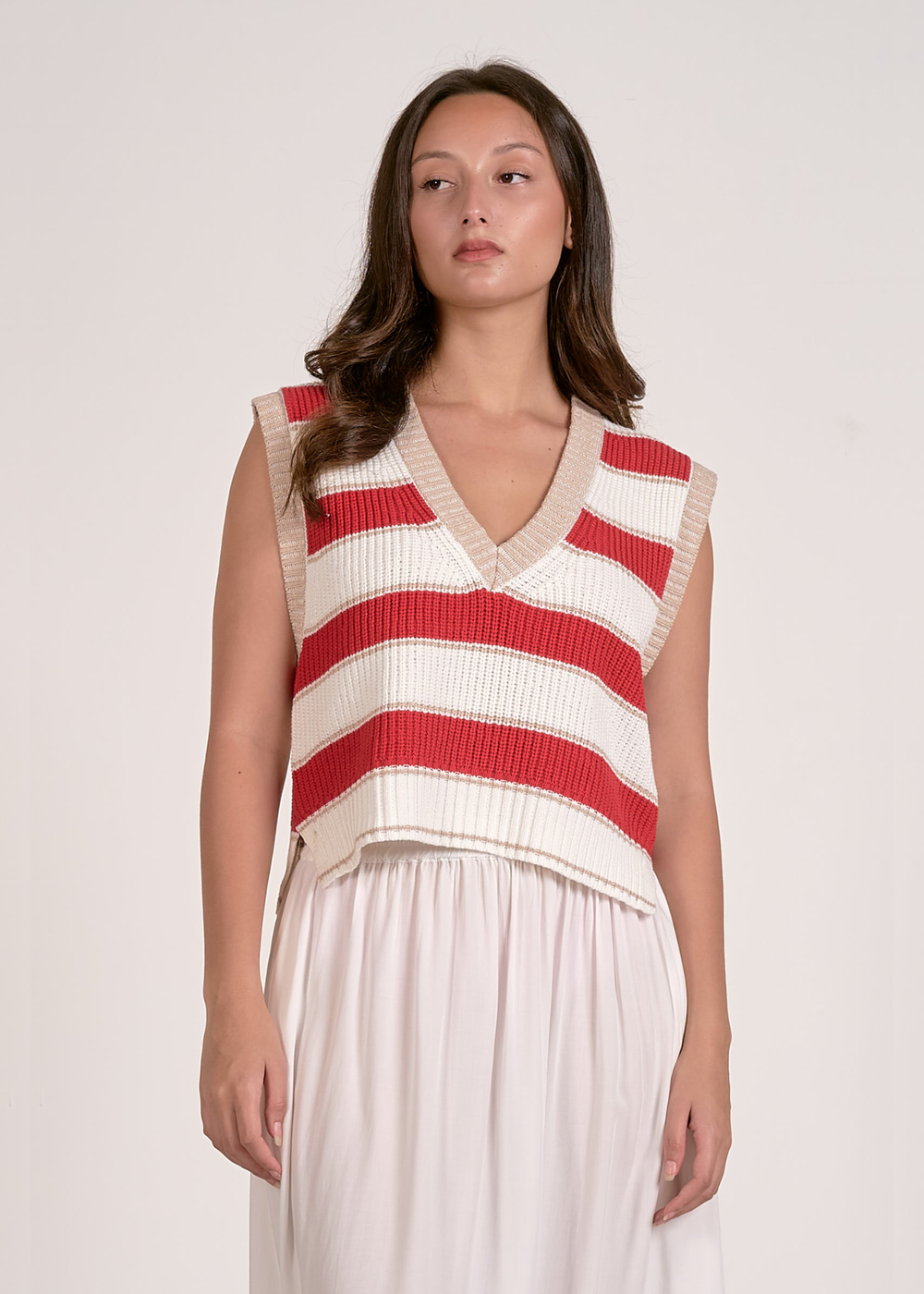 Woman wearing a red and white striped sweater vest and a white skirt