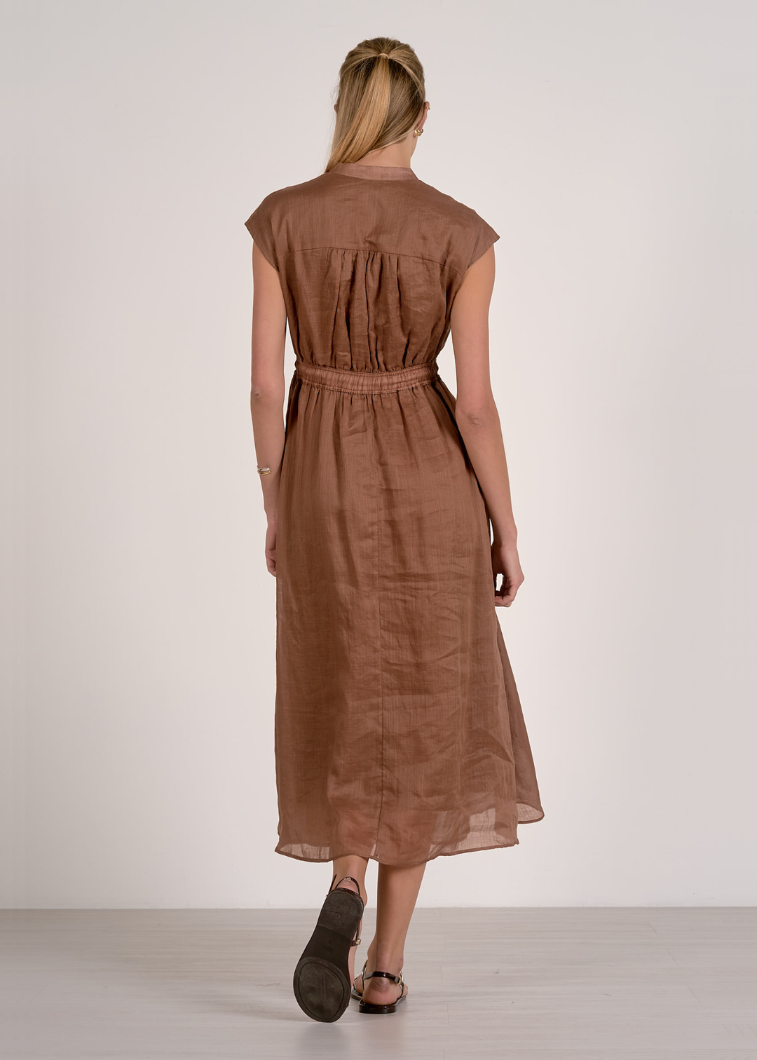 Woman turned around wearing a brown midi dress with flats