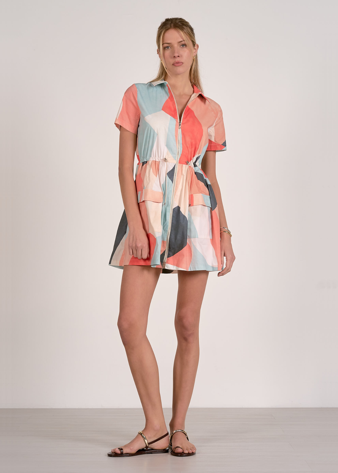 Woman wearing a short sleeve mini dress with a collared neckline and a pastel print pattern