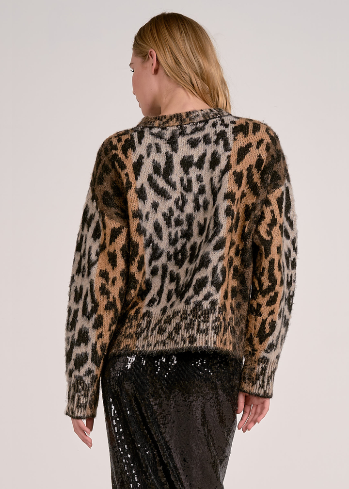 Woman turned around wearing a cheetah print sweater with a black sequin skirt