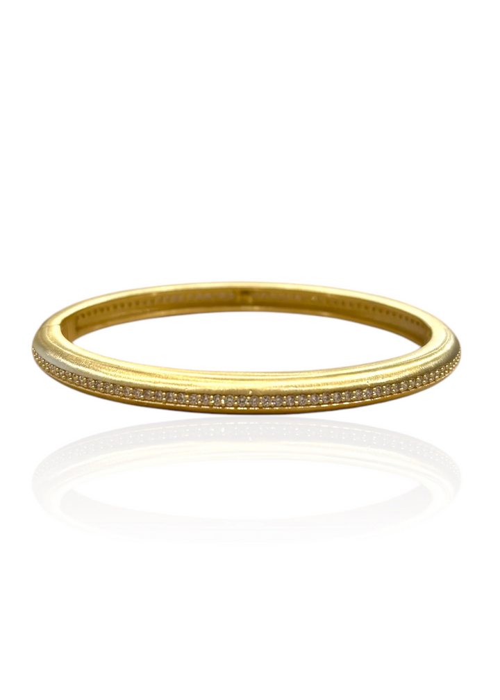Gold bangle bracelet with pave CZs on a white background