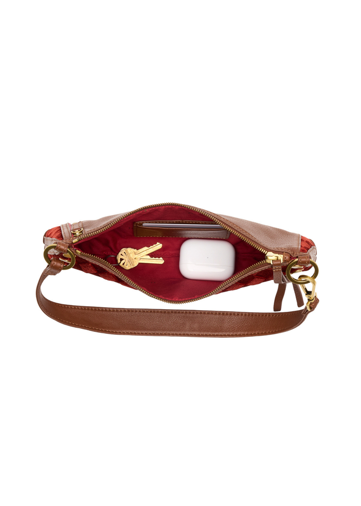 Red velvet handbag with brown and gold accents sitting open on a white background