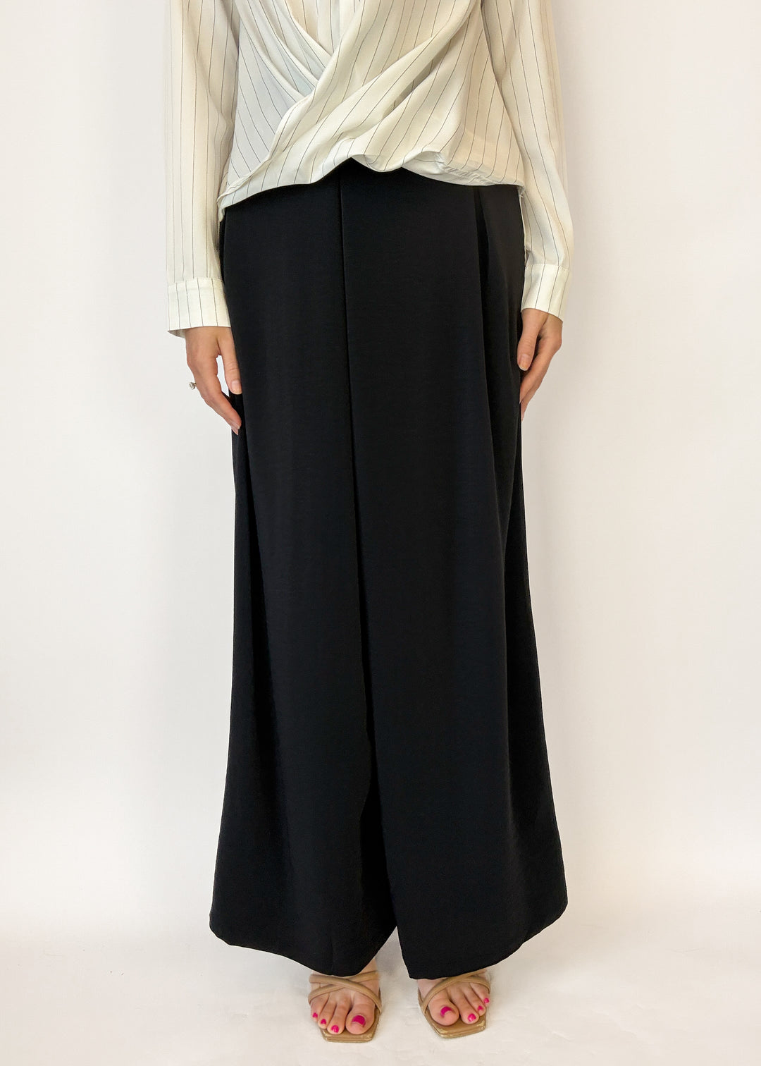 Person wearing a white blouse and black wide-leg pants on a white background
