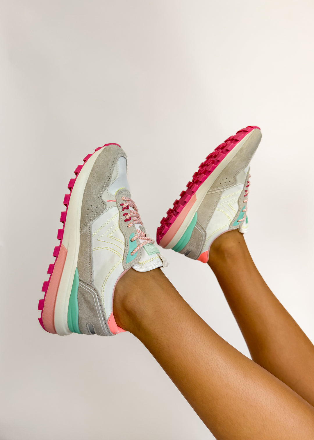 Colorful sneakers with pink soles on a neutral background