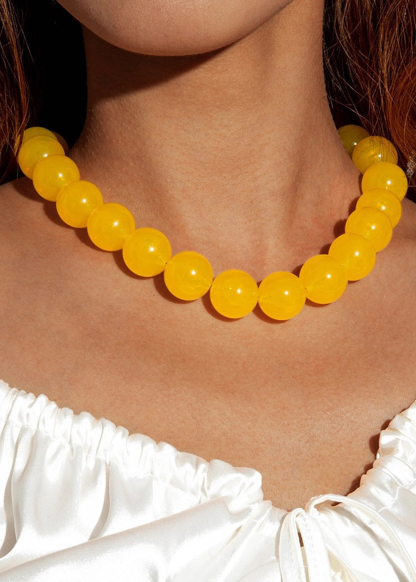 Yellow beaded necklace worn by a person in a white top