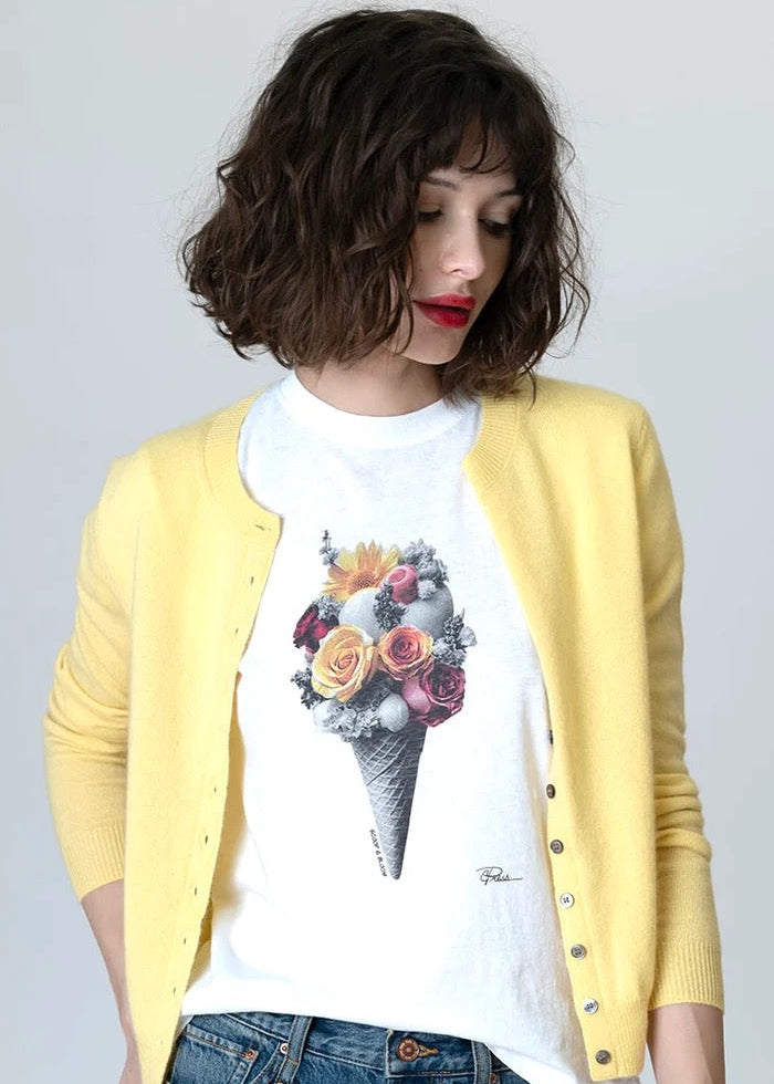 Person wearing a yellow cardigan over a white t-shirt with a colorful ice cream cone design, standing against a plain background.