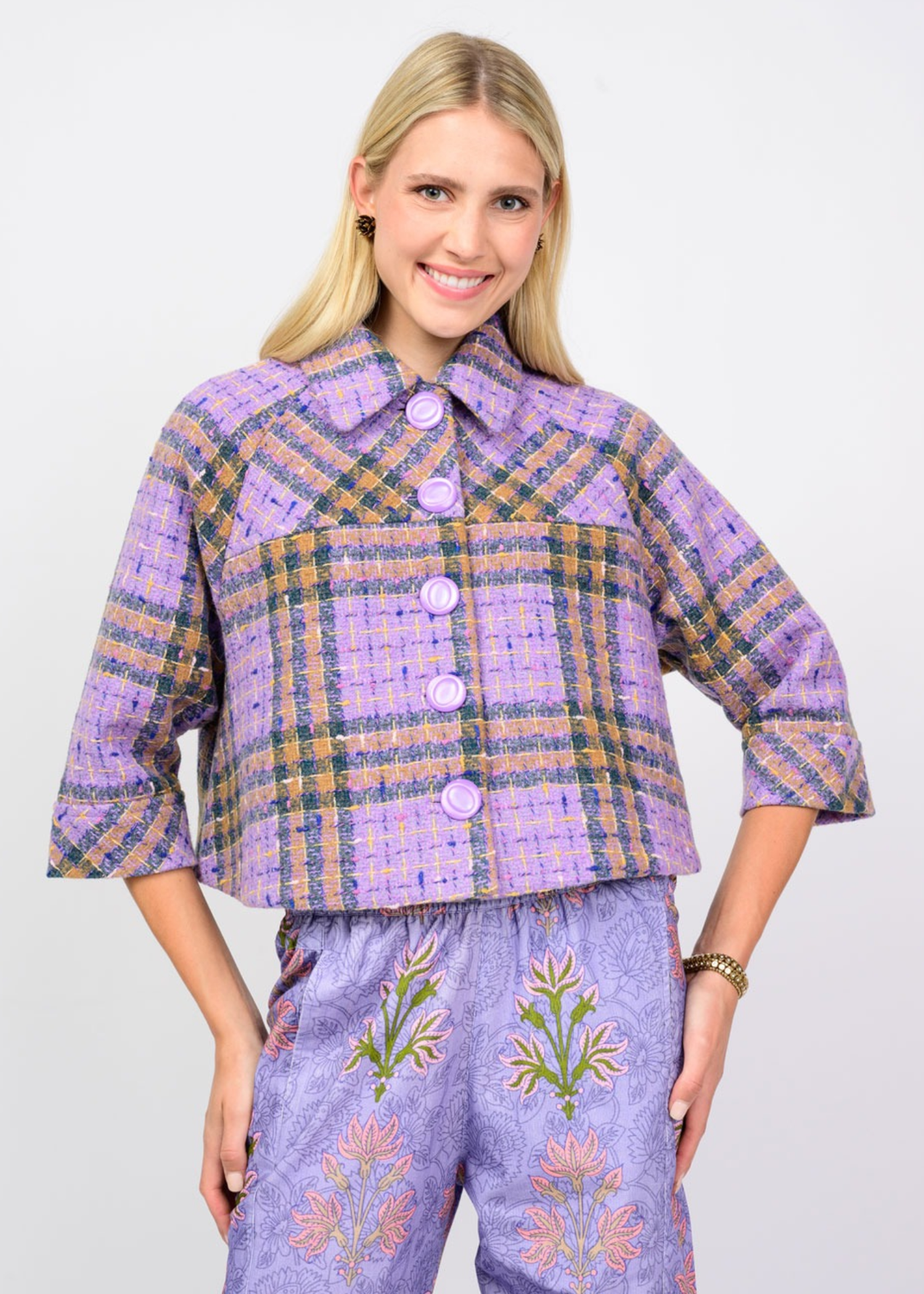 Woman wearing a purple plaid jacket against a white background