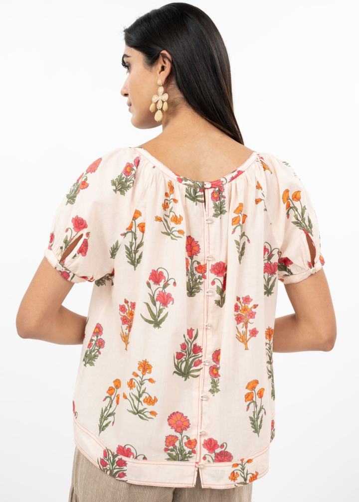 Woman turned around wearing a floral top with brown pants
