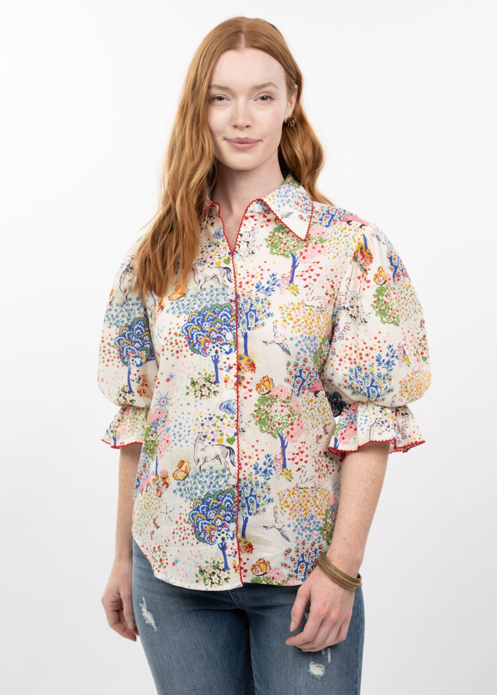 Woman wearing a multicolor patterned button down top with puff sleeves and jeans