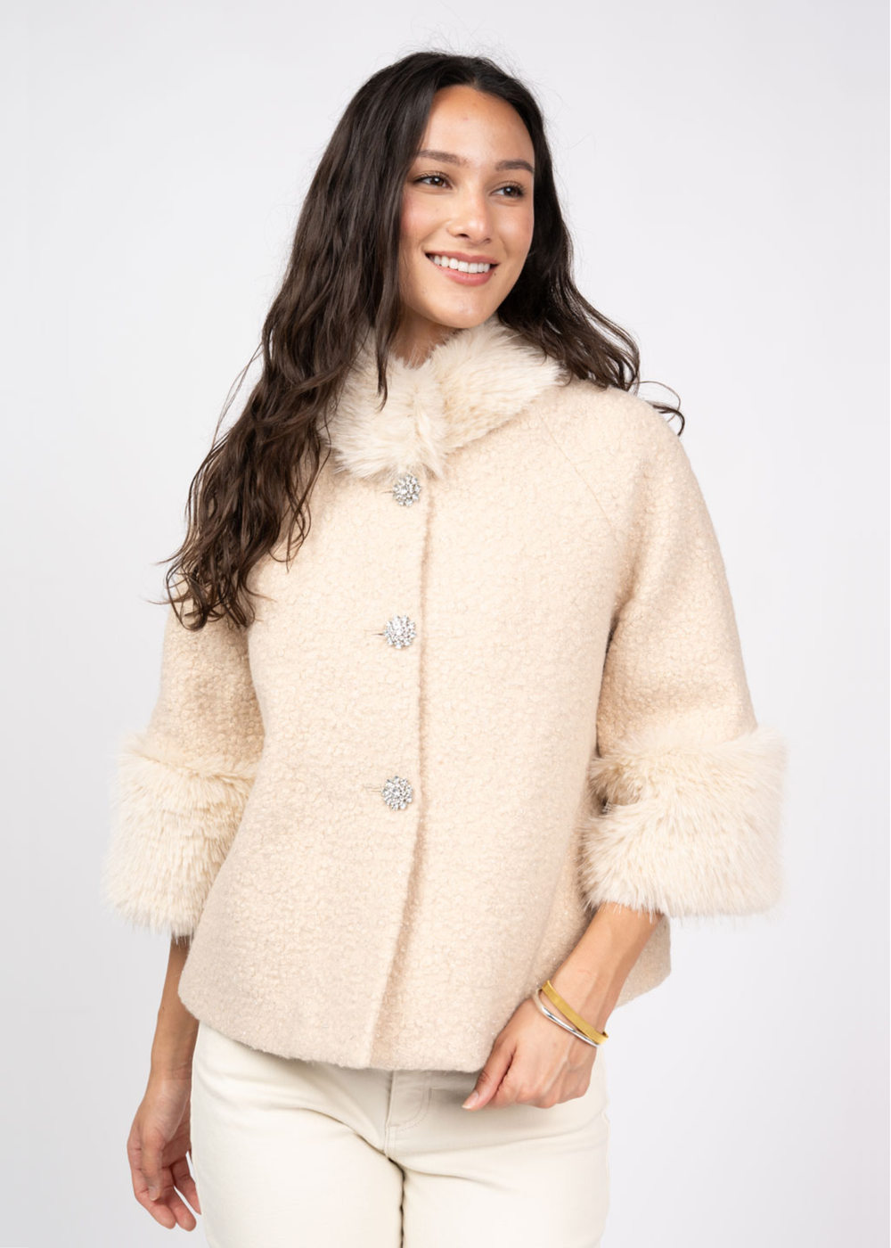 Woman wearing an ivory coat against a white background